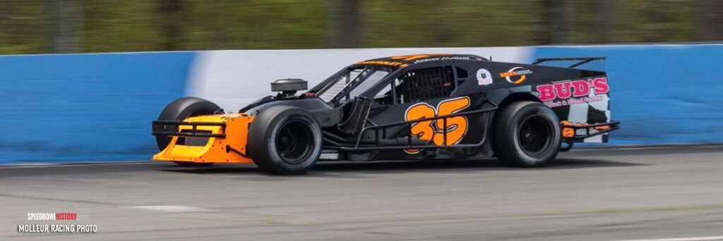 Race car number 55 speeding on a track with vibrant sponsor logos.