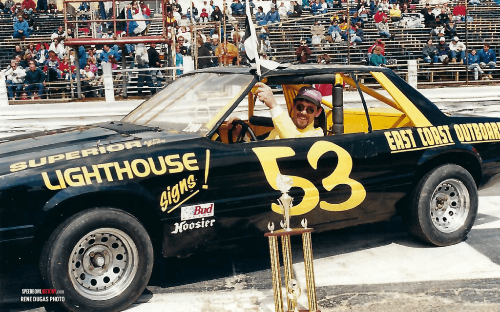 A black race car with the number 53 in a stadium.